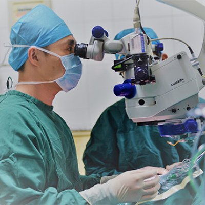 Surgeon wearing scrubs looking into eye machine 